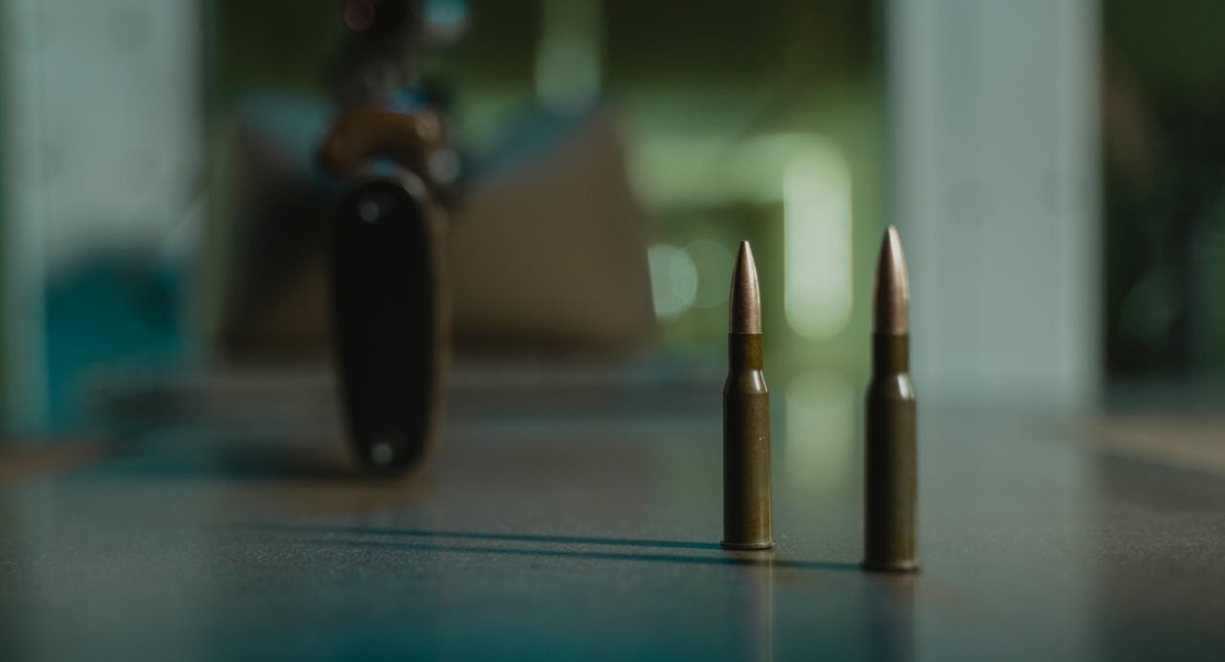 bullets on a flat surface with a gun in the background