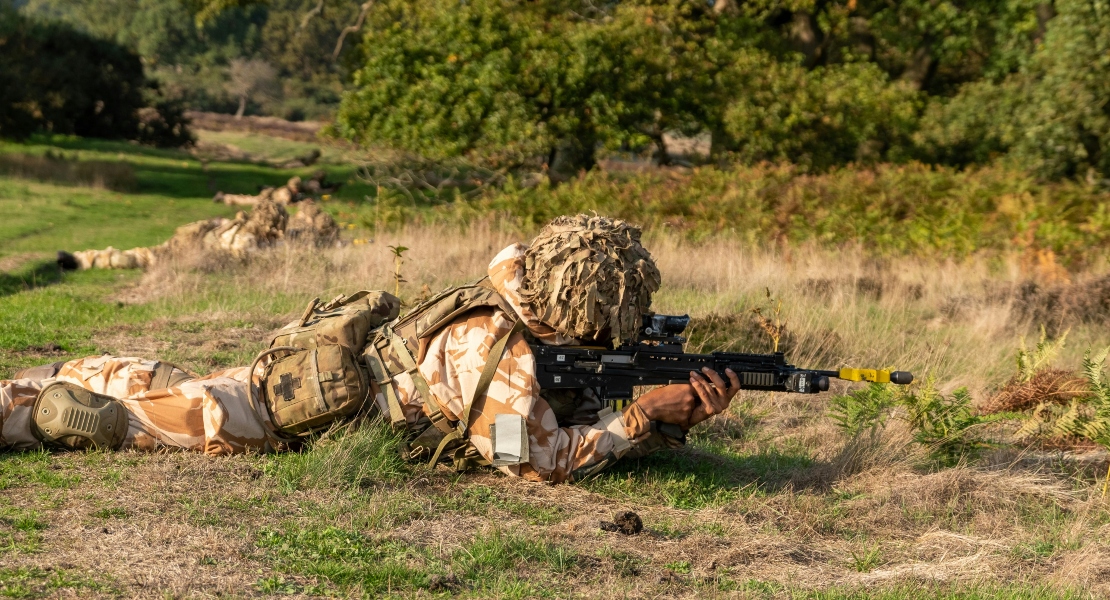Soldier prone in muddy terrain demonstrating AK reliability under harsh battlefield conditions.