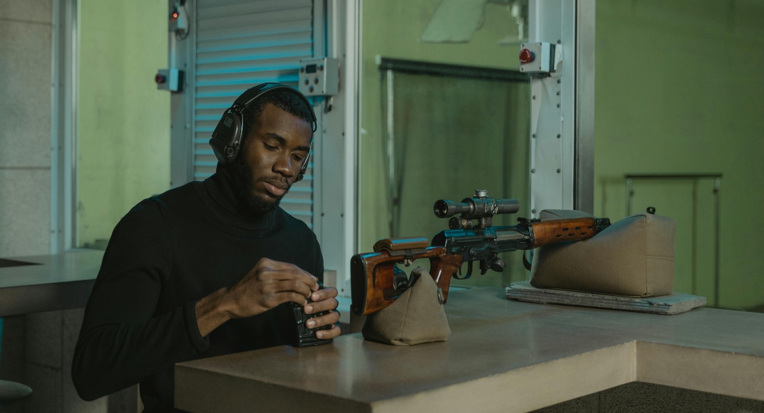 Man holding brown wooden rifle illustrating cerakote vs nitride vs parkerized firearm coatings and how the best option depends on intended use.