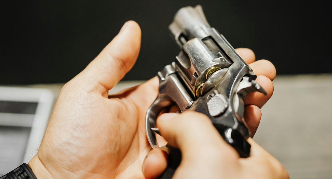 Person holding a firearm while inspecting trigger components for visible wear and surface degradation.