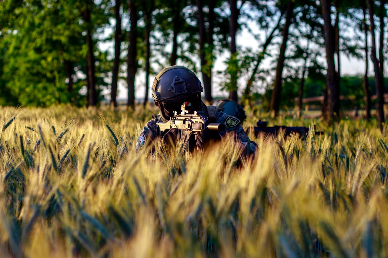 a man in tall grass holding mp5