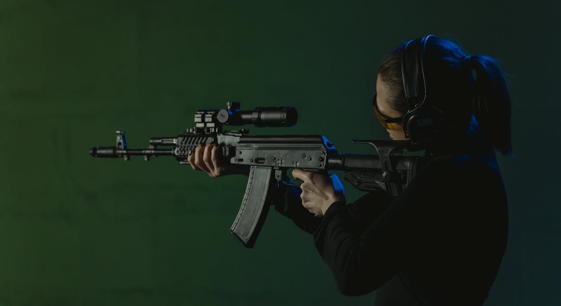 Person aiming a rifle while looking toward a shooting target
