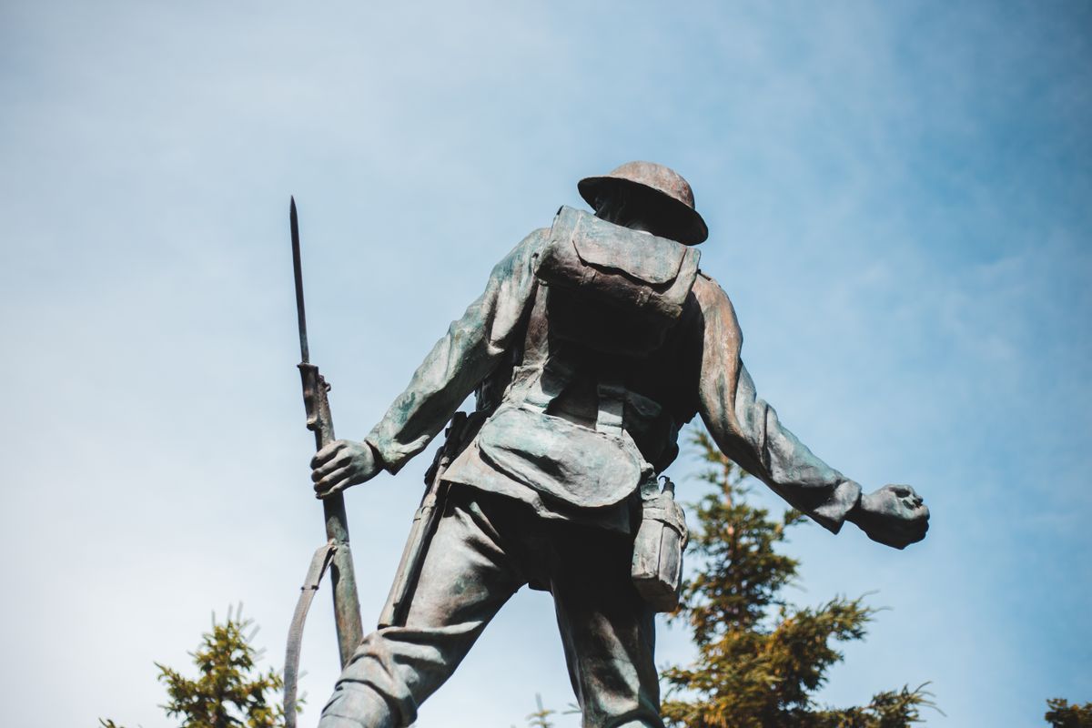 a soldier holding a gun against a clear blue sky