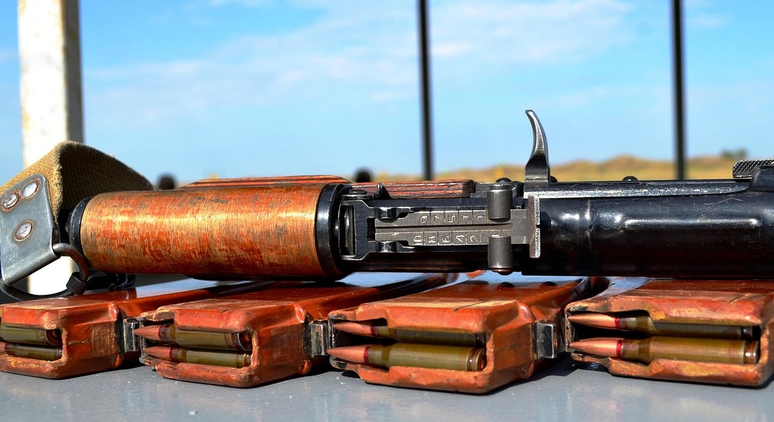 AK rifle with loaded magazines on a bench