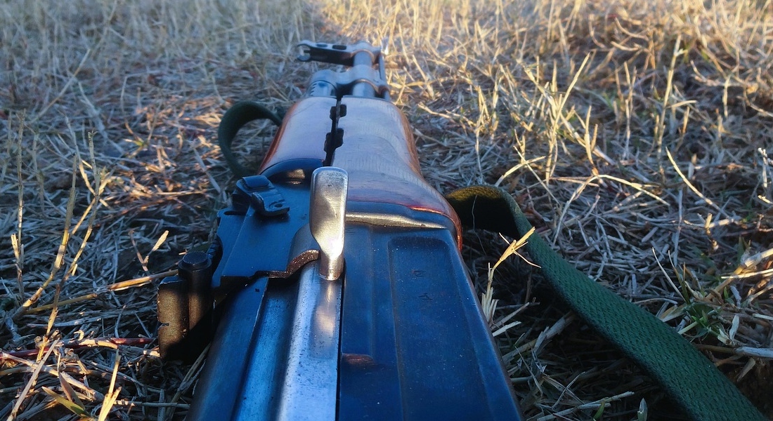 AK rifle resting in an open field