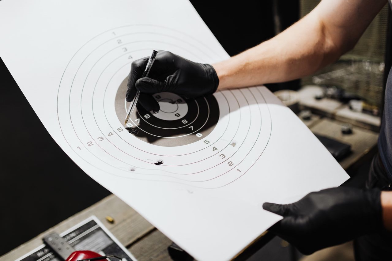 Person marking hits on a paper shooting target