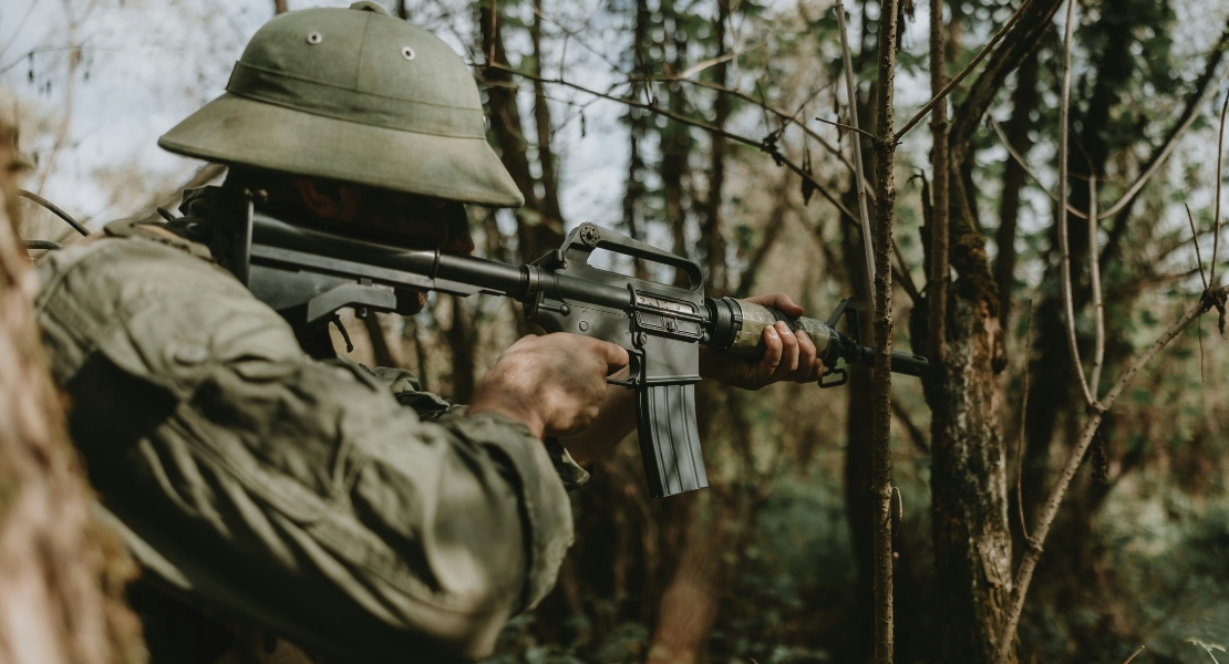 Soldier carrying an M16-style rifle representing the mil-spec fire control group history and military standardization.