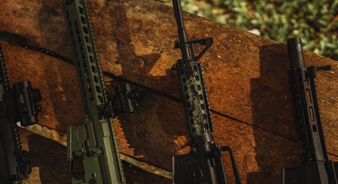 few rifles propped against the wooden board