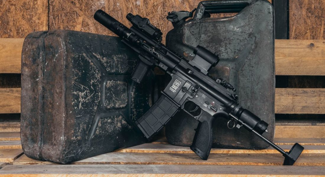 a military-style rifle rests against metal canisters