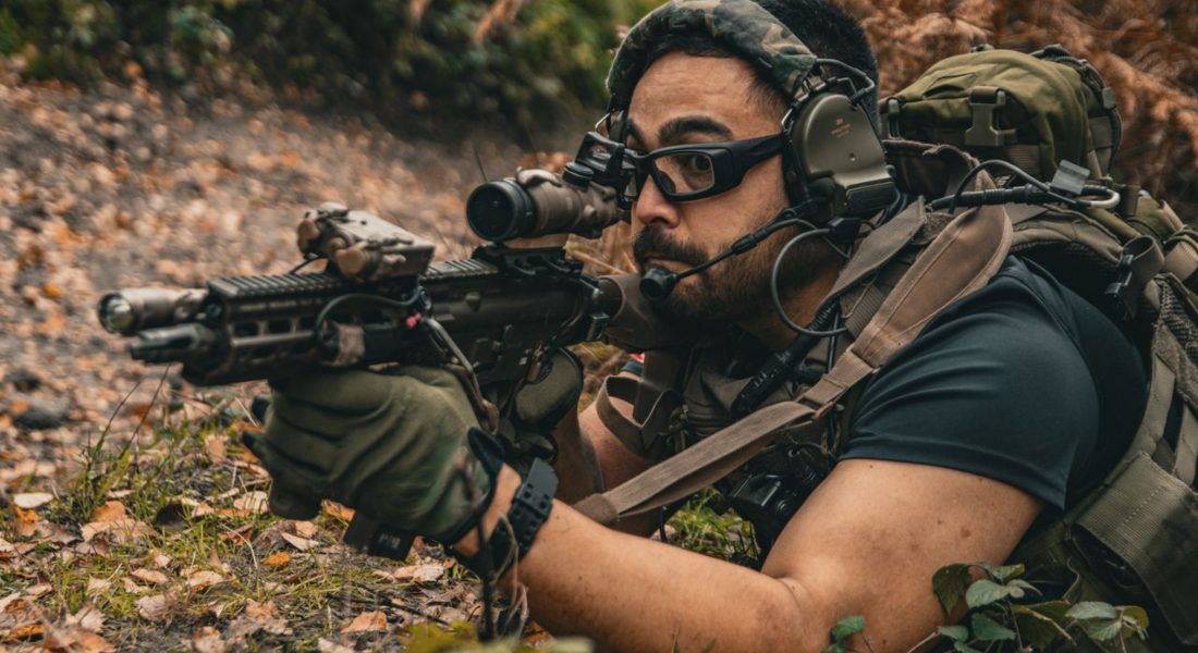 a man in military uniform in a forest with a mp5k