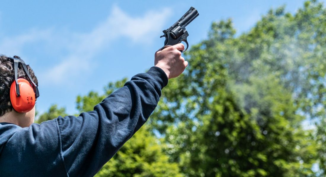 a person firing a starting pistol outdoors with blue sky