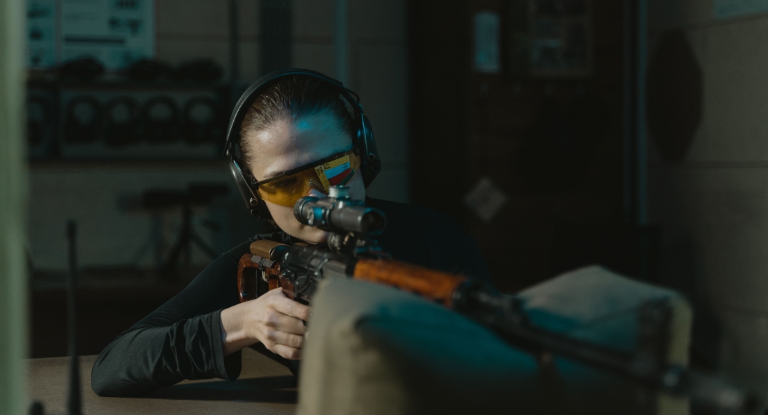 A woman aiming with a rifle.