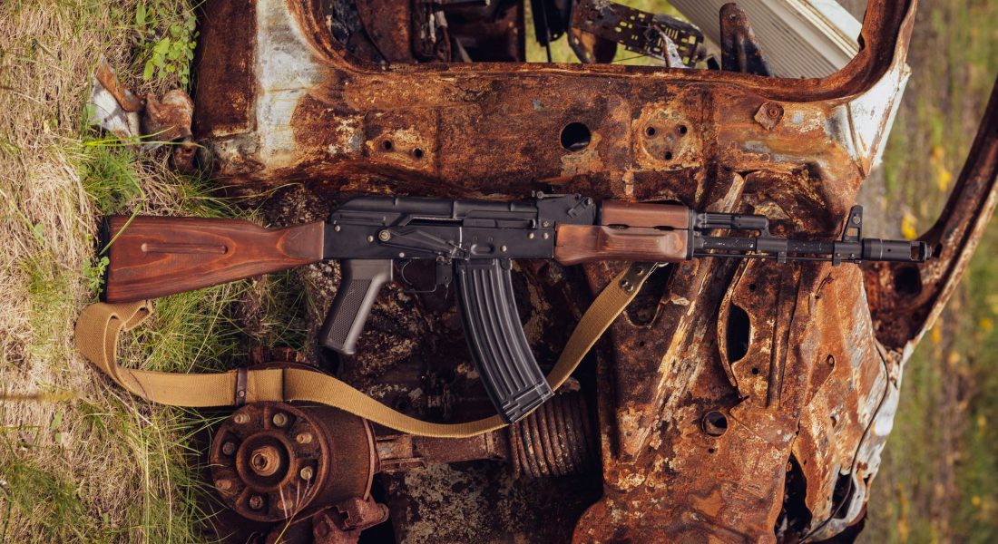 Rifle leaning against a rusty, abandoned car