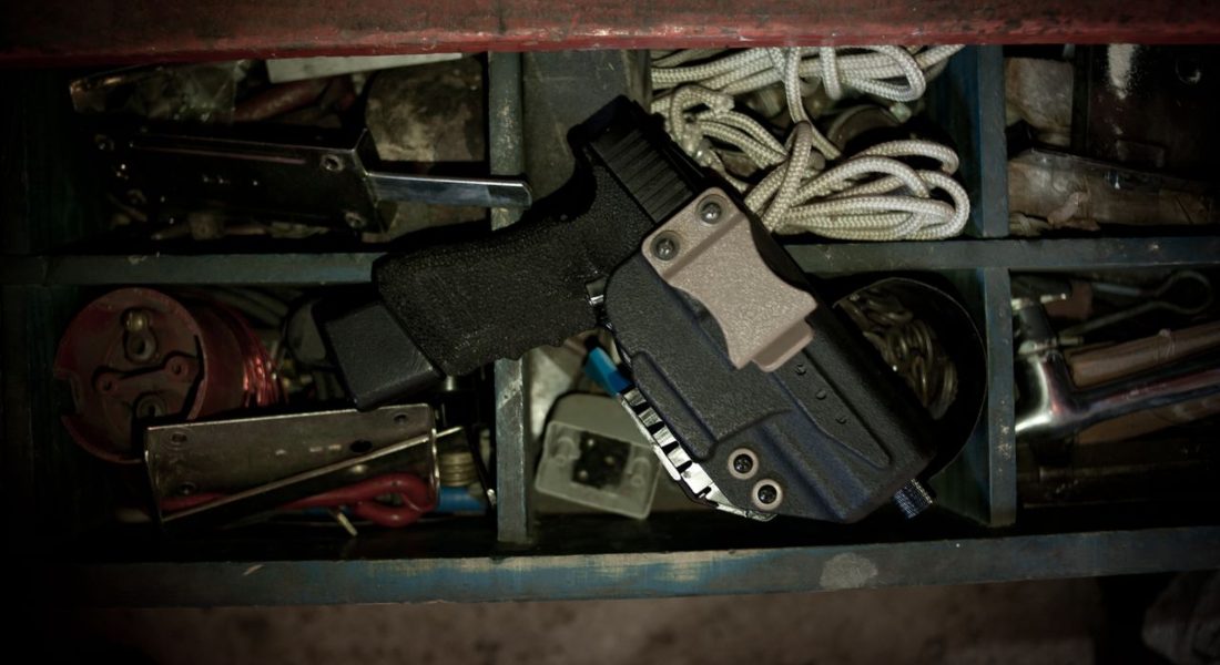 a detailed view of a pistol in a holster placed on a box of trinkets