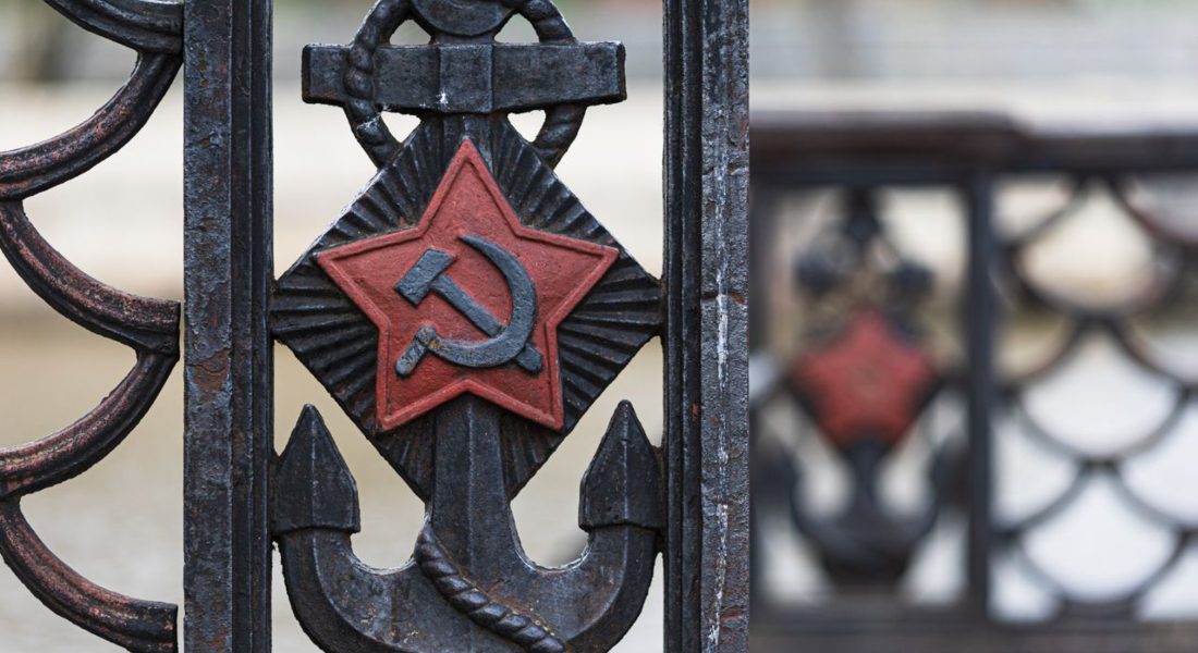 Close-up of an old iron fence featuring a Soviet anchor design