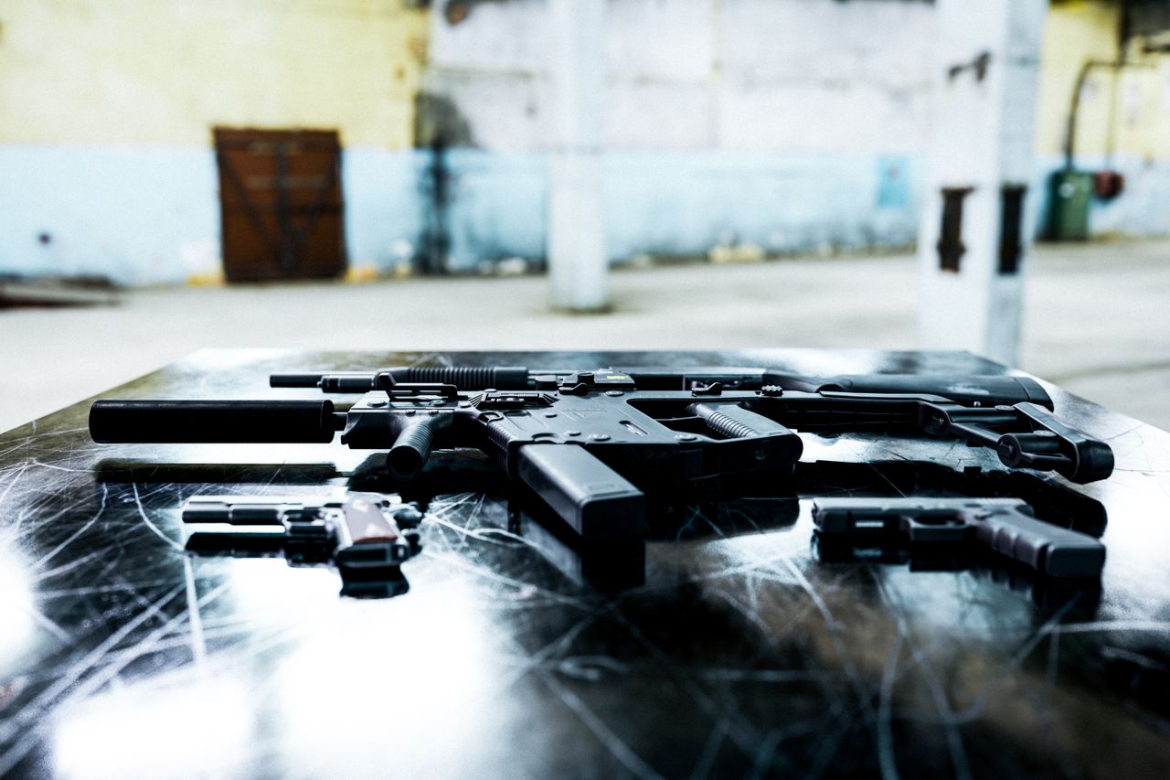 Various firearms displayed on a scratched metal table