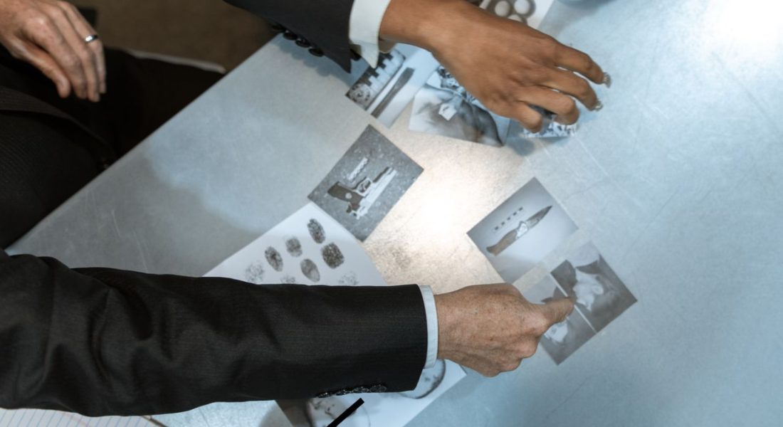FBI detectives analyzing black and white photos of guns and suspects
