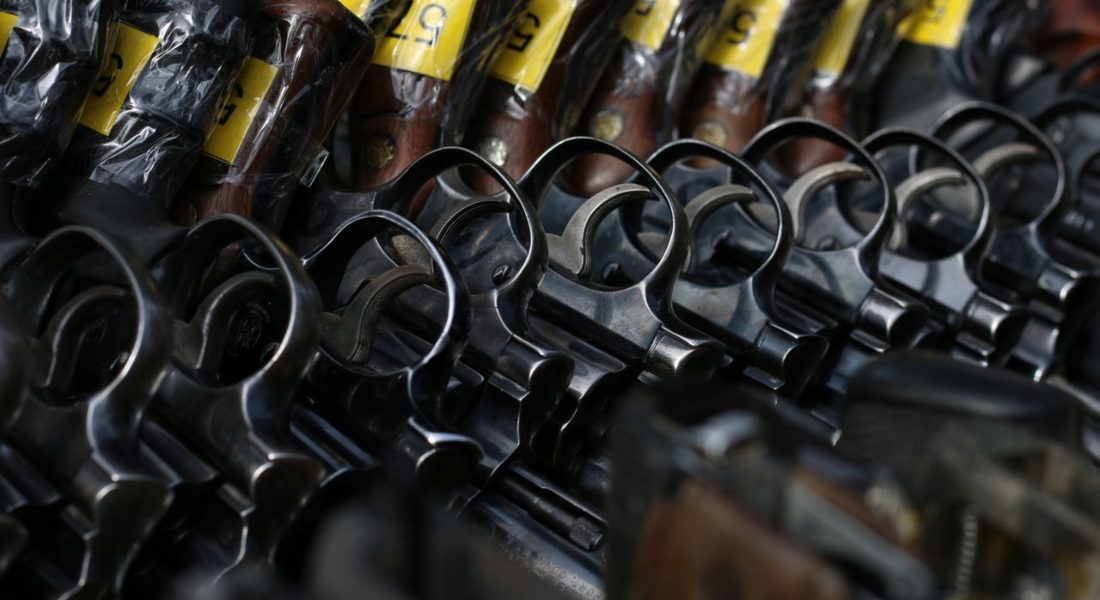 a close-up image of revolvers with yellow tags arranged on a rack