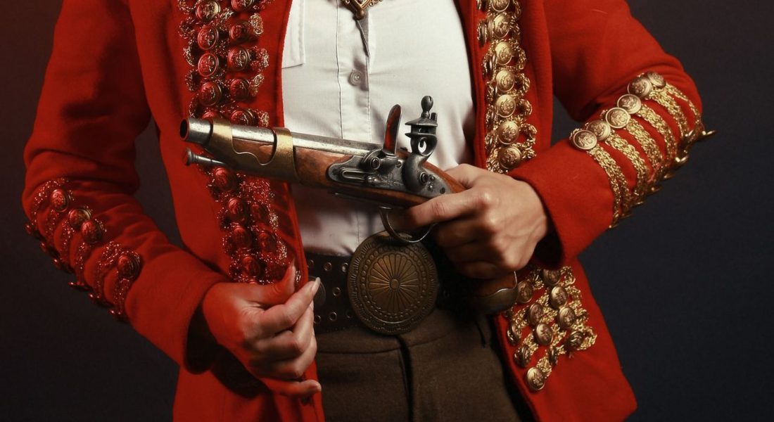 a woman in a red vintage military-inspired costume holding a gun