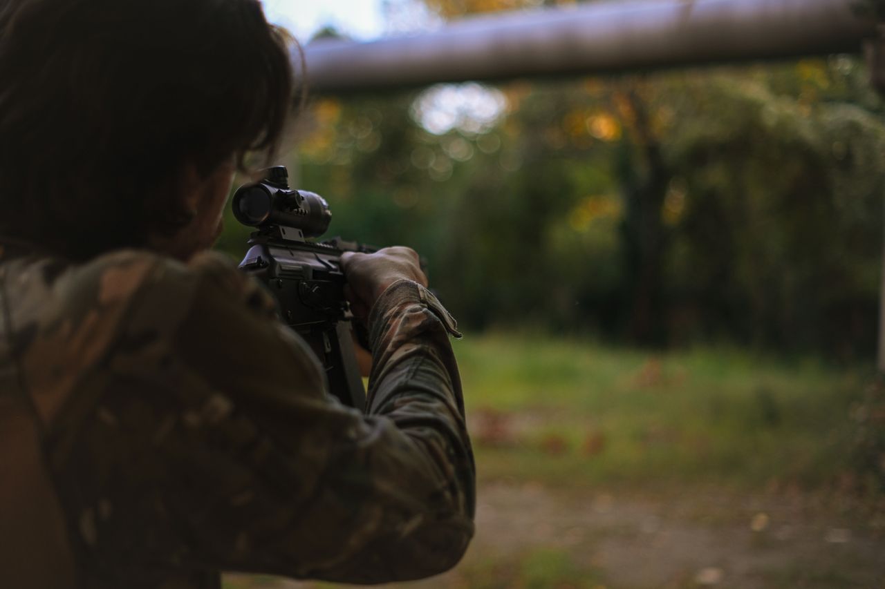 a person in camo gear aiming a gun
