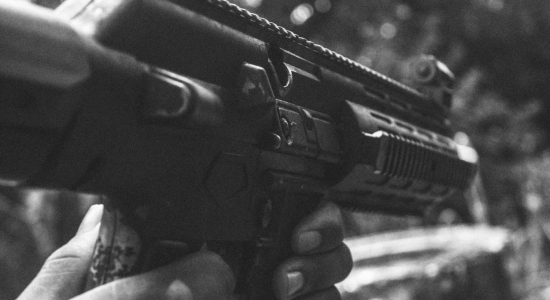 Monochrome image showing hands holding a firearm