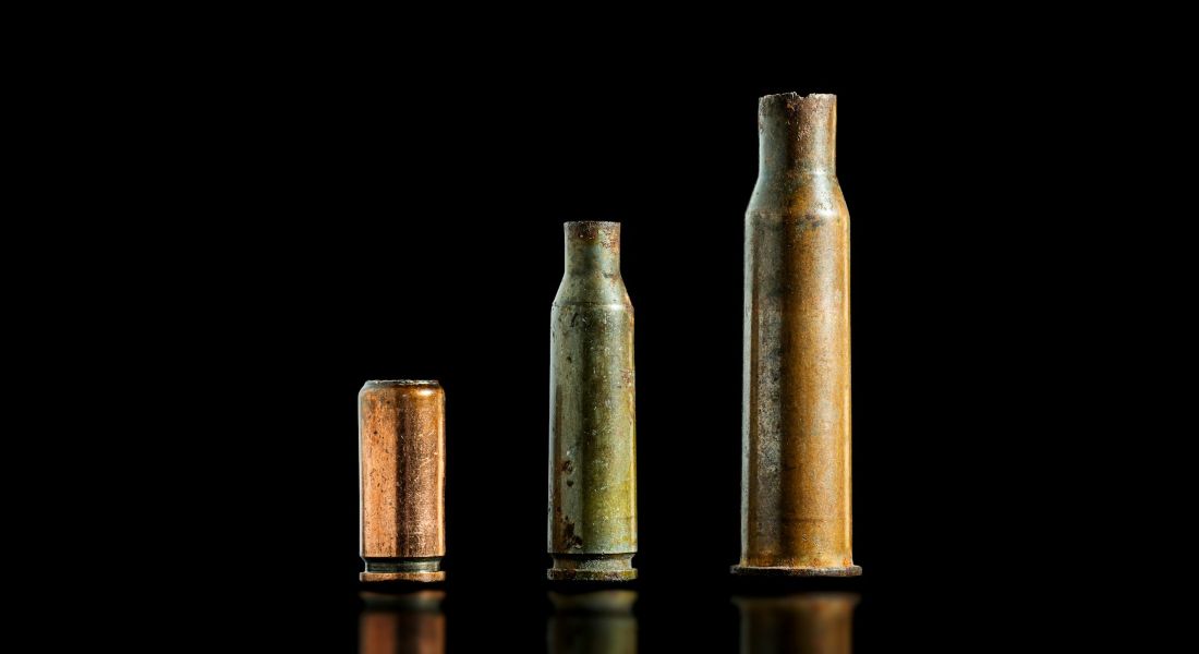 Three used bullet casings sit on black background