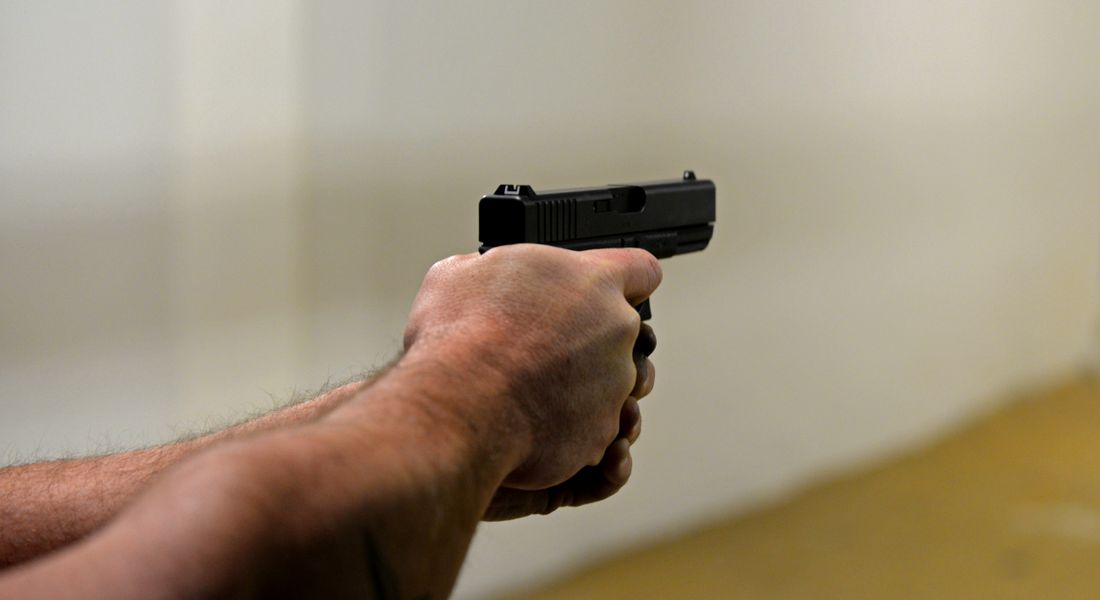 Close-up of a shooter's two-handed grip on a pistol at an indoor range