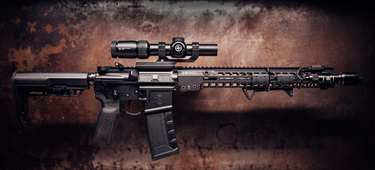 AR-style pistol-caliber carbine with a scope on a dark rusted metal background