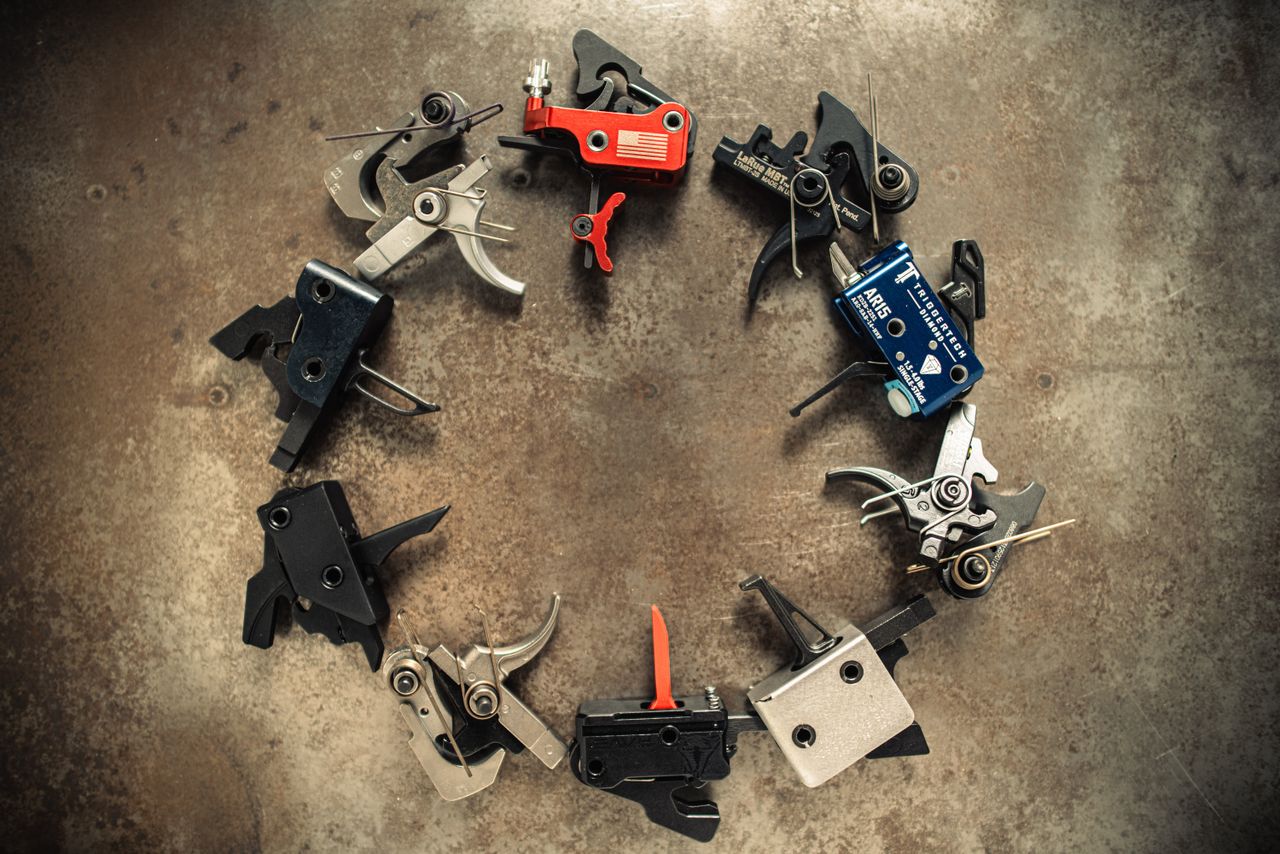 Aerial view of arranged AR-15 drop-in triggers forming a circle on a rusted metal surface