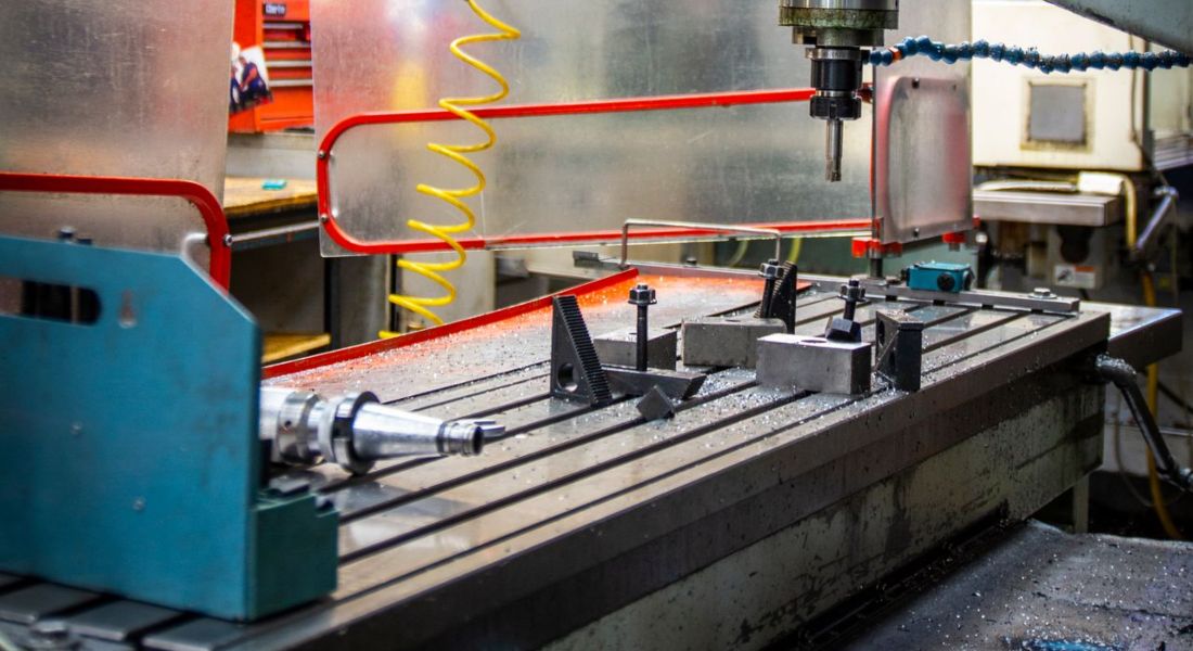 Close-up of an industrial CNC lathe in a bustling machine shop setting