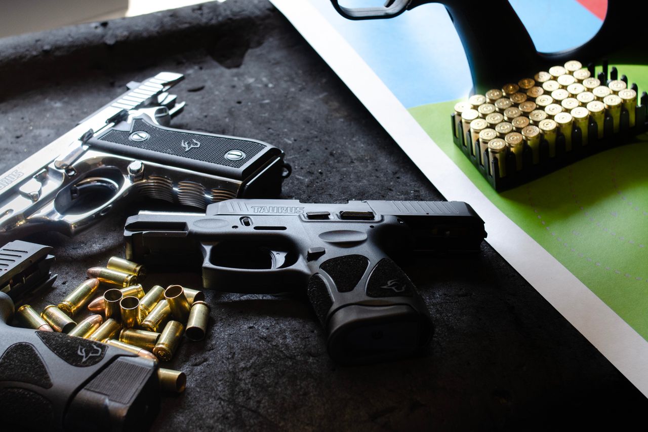 Two semi-automatic pistols and loose brass ammunition on a shooting range table