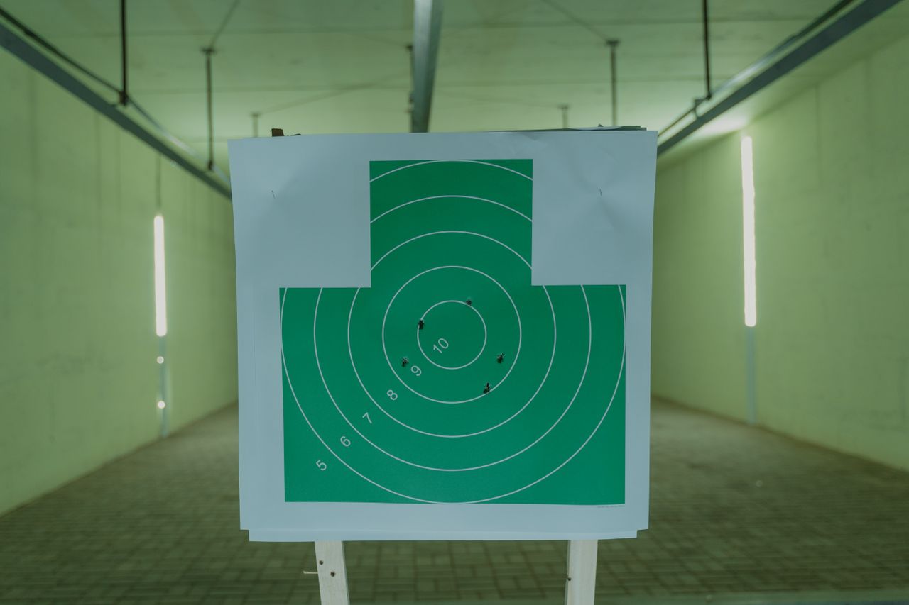 a green circle target with bullet holes at an indoor shooting range