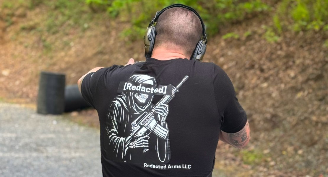 Shooter in a Redacted Arms shirt firing a rifle at an outdoor range